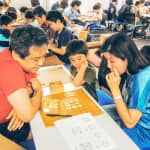 Parents and children are solving puzzles together.